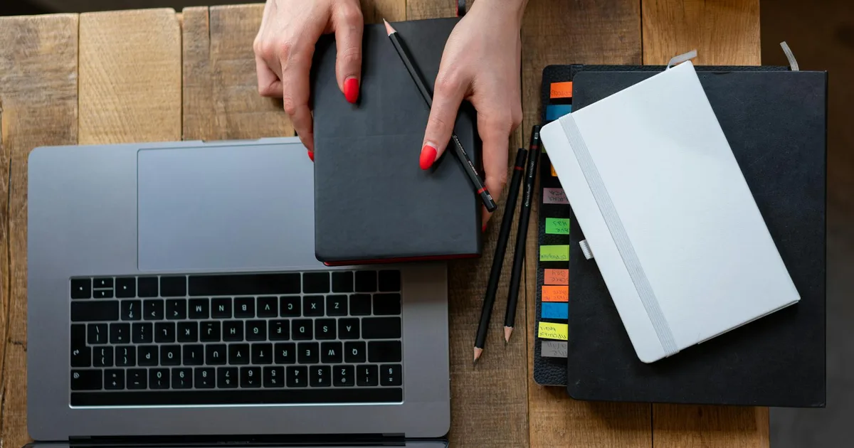 Top-down view of a desk featuring a laptop, planner, and notebooks, ideal for productivity themes.
