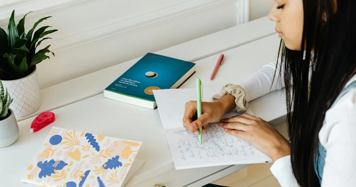 Teenager focused on writing in a notebook at a calm home desk, illustrating productivity and mental clarity.