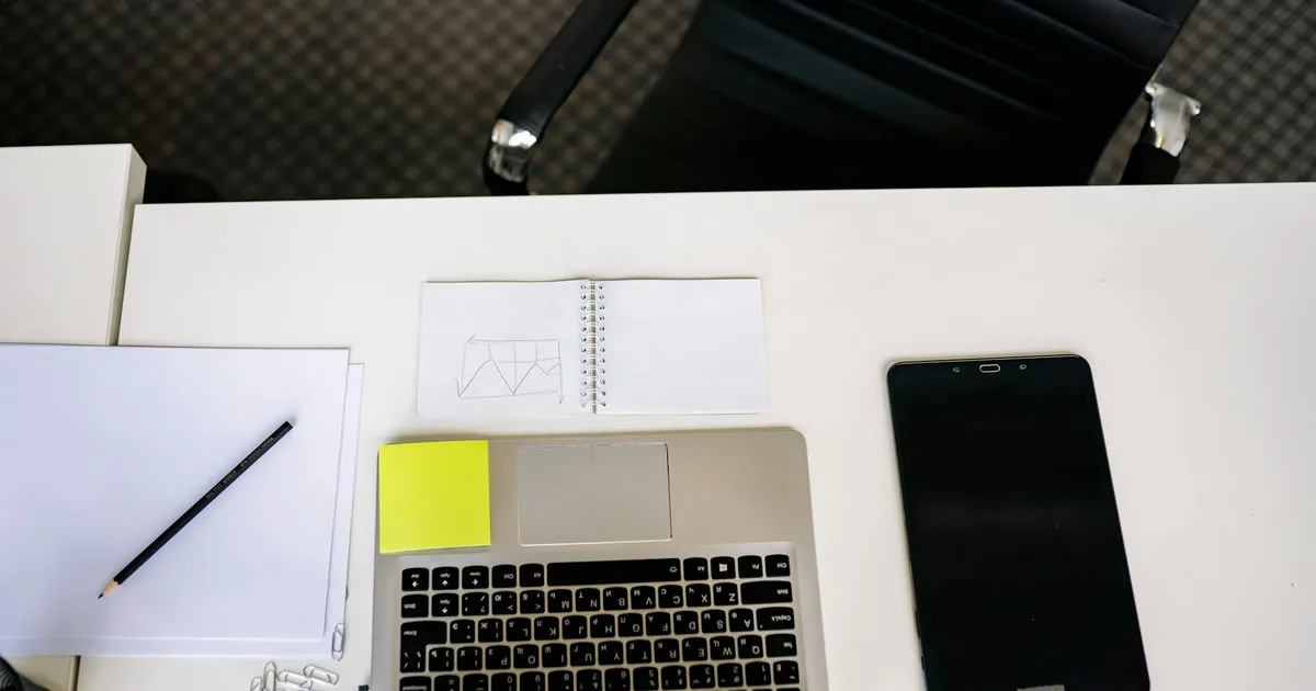 A tidy office desk with a laptop, tablet, and stationery, representing an organized workspace for productivity.