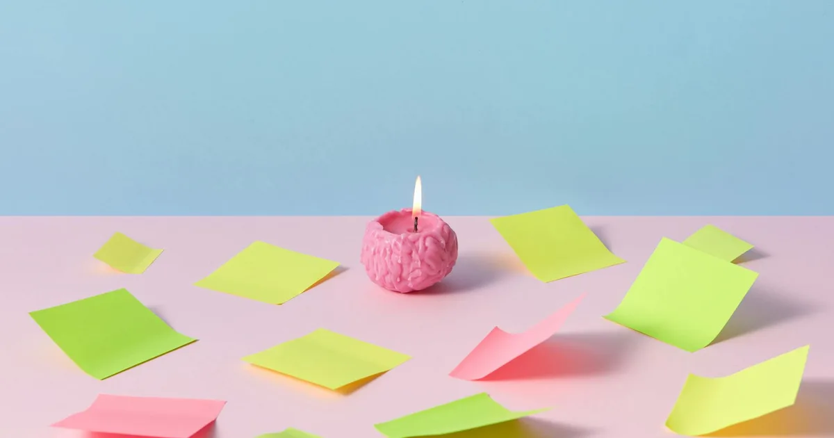 A pink brain candle lit among colorful sticky notes on a pastel background, symbolizing creativity and playful brainstorming.